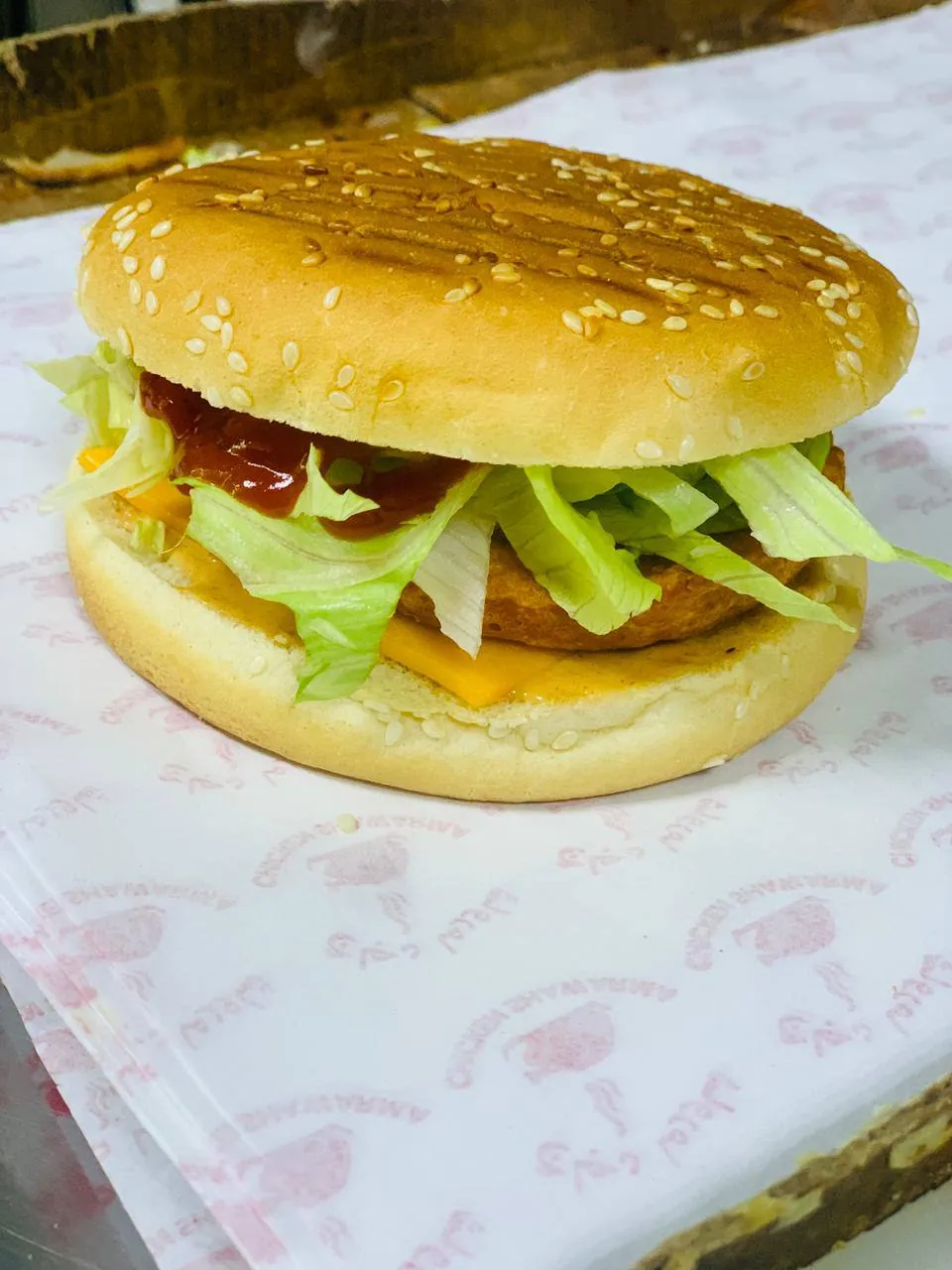 Fried chicken fillet burger with lettuce and ketchup in a sesame bun