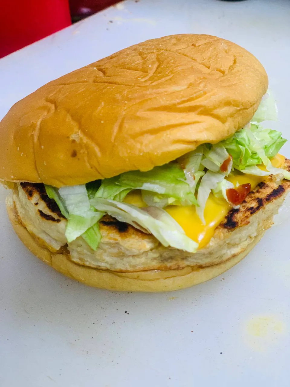 Grilled chicken burger with melted cheese and shredded lettuce