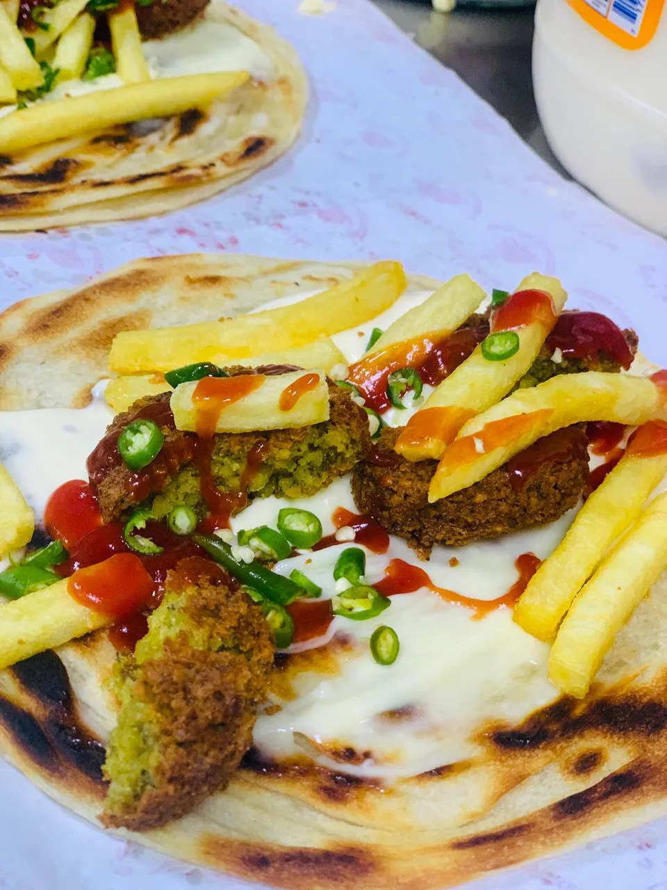 Falafel with fries, green chilli and white sauce on flatbread