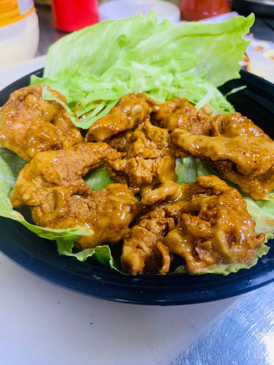 Fried chicken pieces coated in sauce on a bed of lettuce