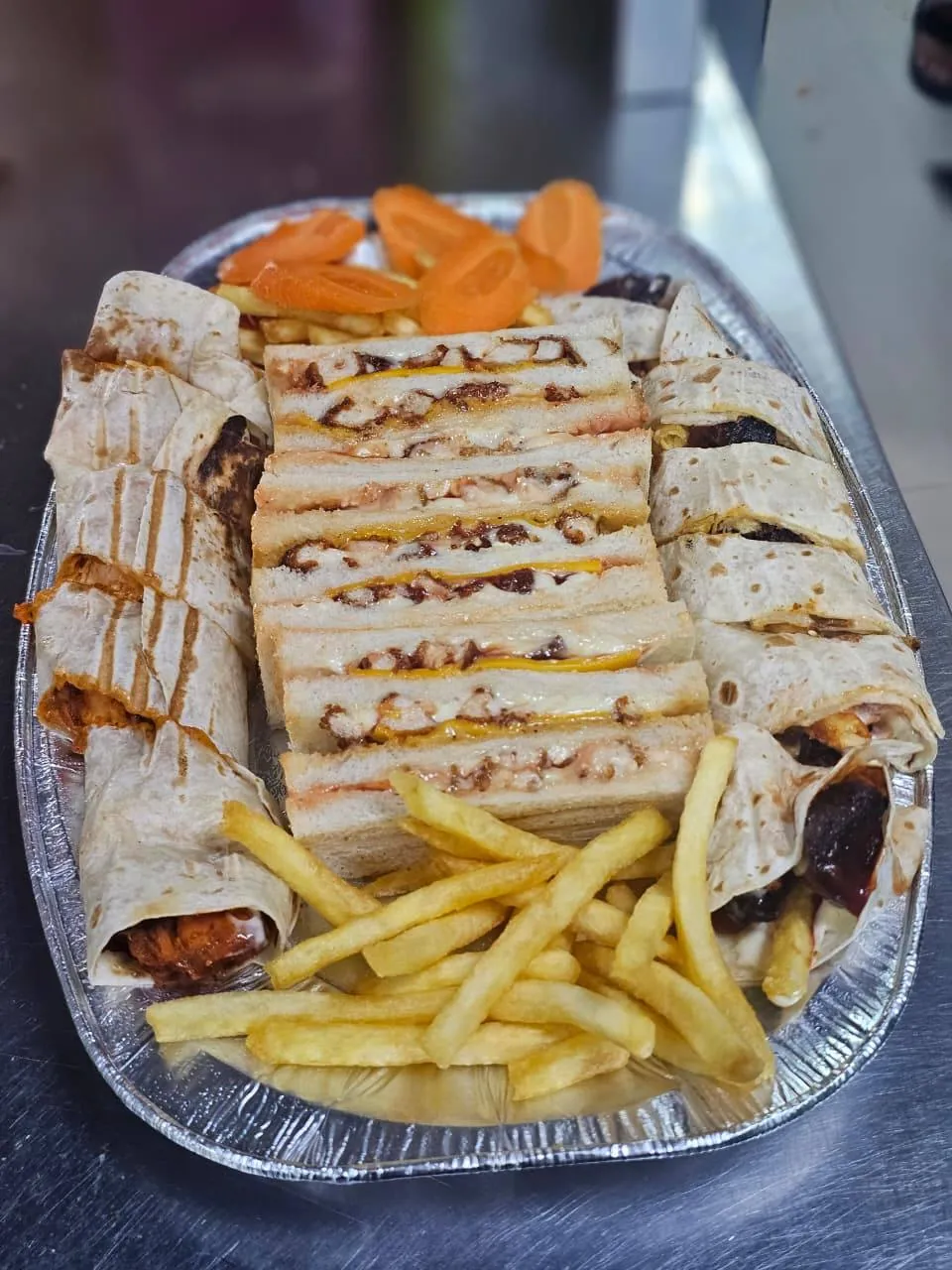 Platter of grilled wraps, club sandwich triangles and fries