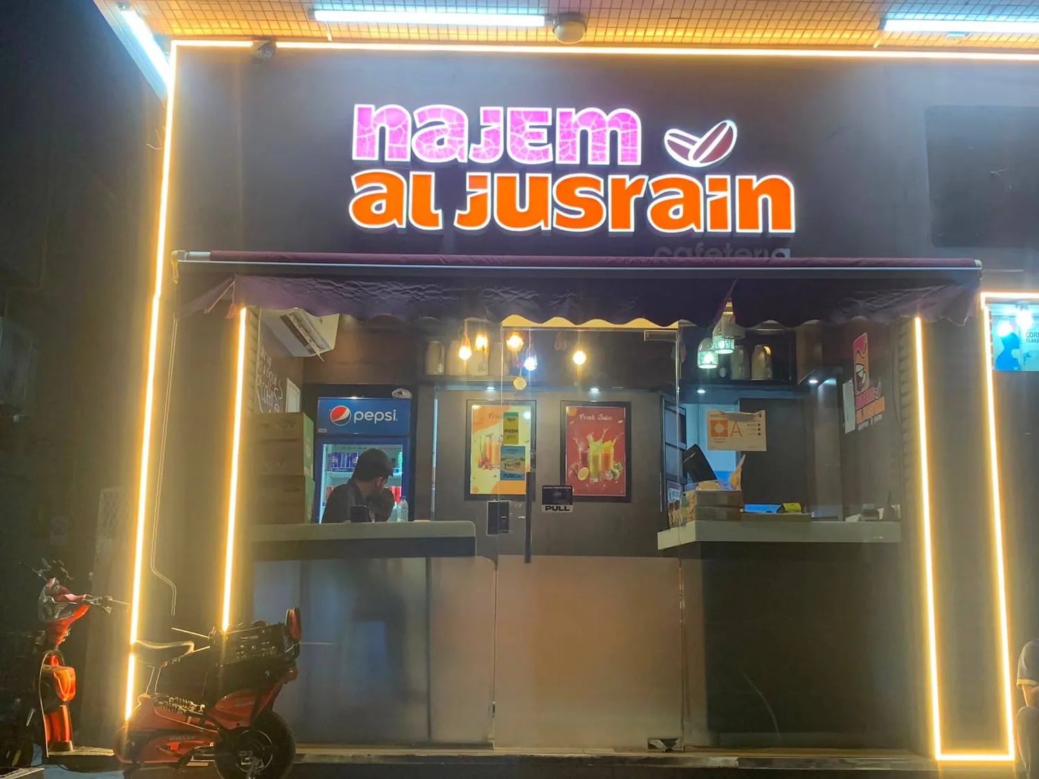 Najem Al Jusrain storefront lit up at night